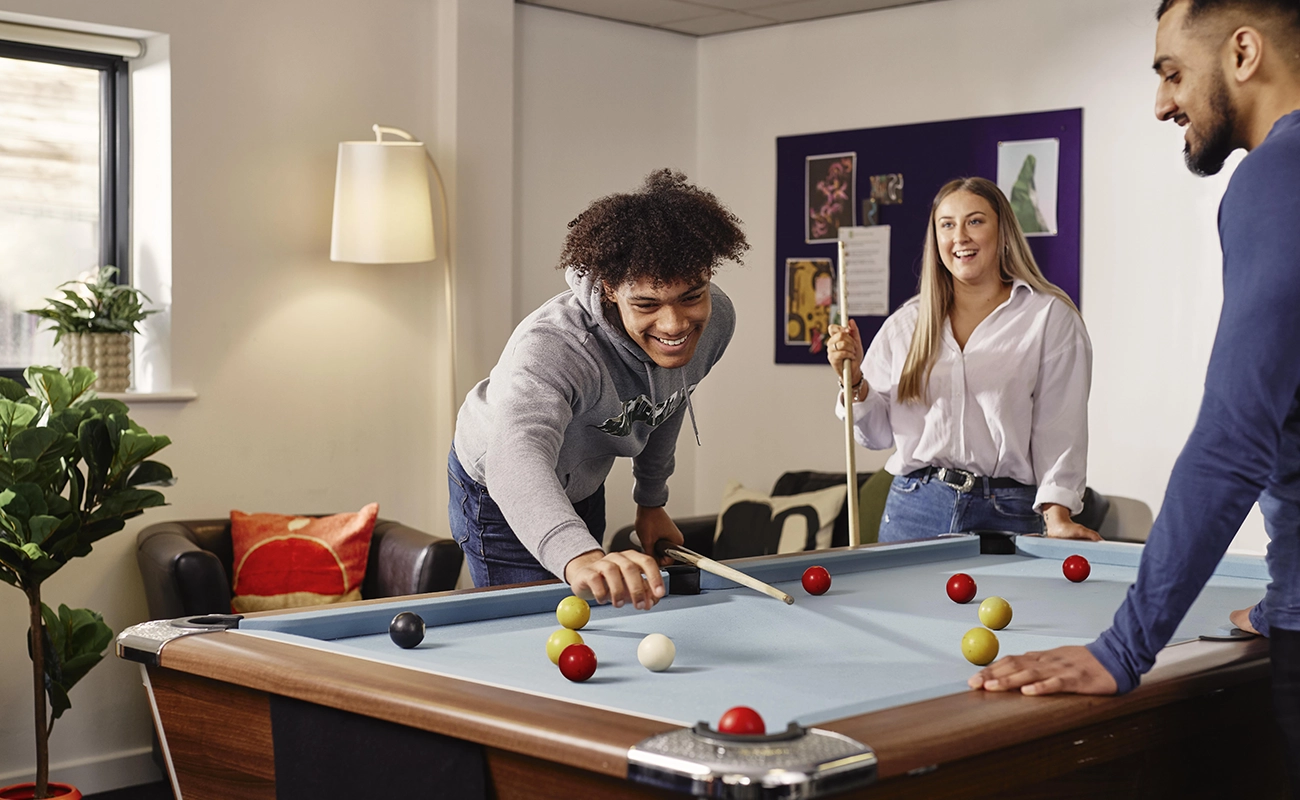 Students playing pool in the common room