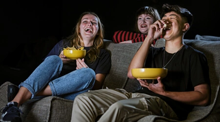 Three friends laughing in a cinema room