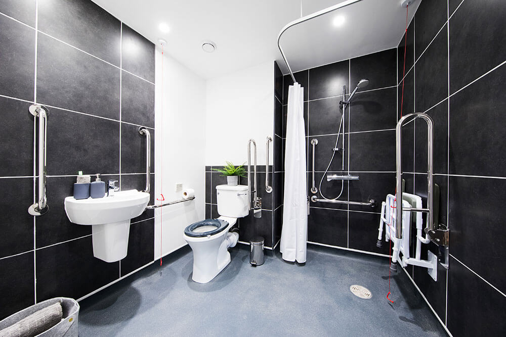 Black tiled bathroom designed for wheelchair users