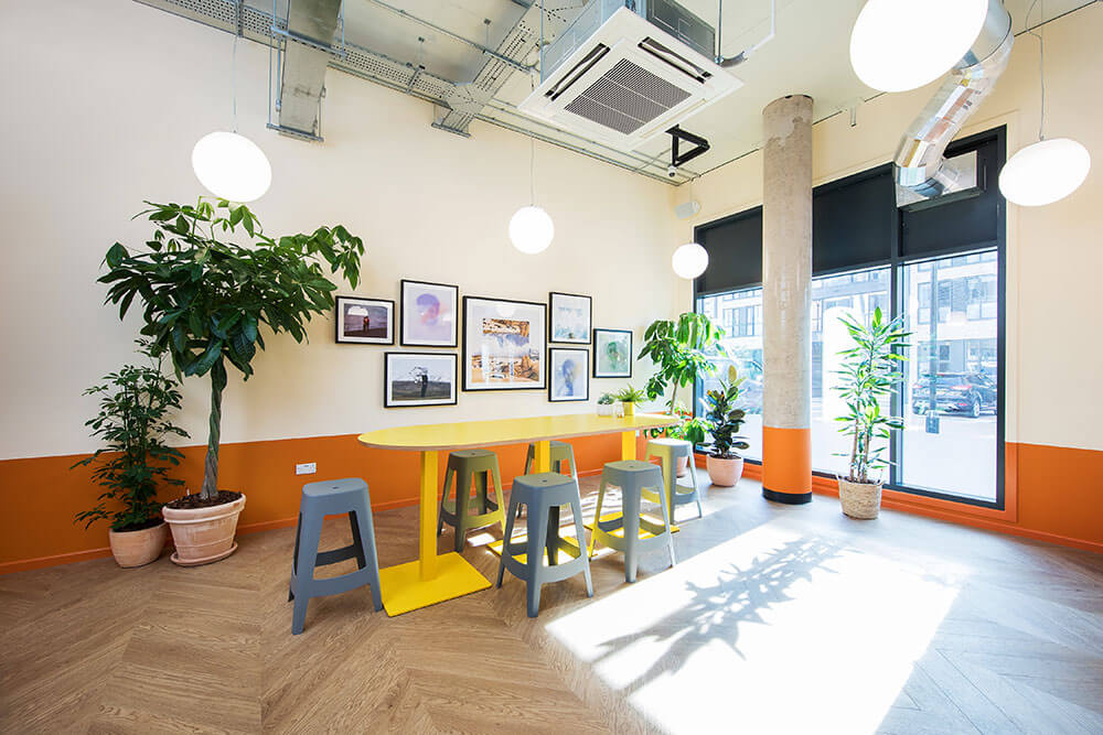 Grey high stools and a yellow table in Parade Green reception area